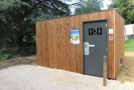 Une vue extérieure des toilettes écologiques, une cabane en bois avec panneau explicatif au parc du Couloumé à Auch